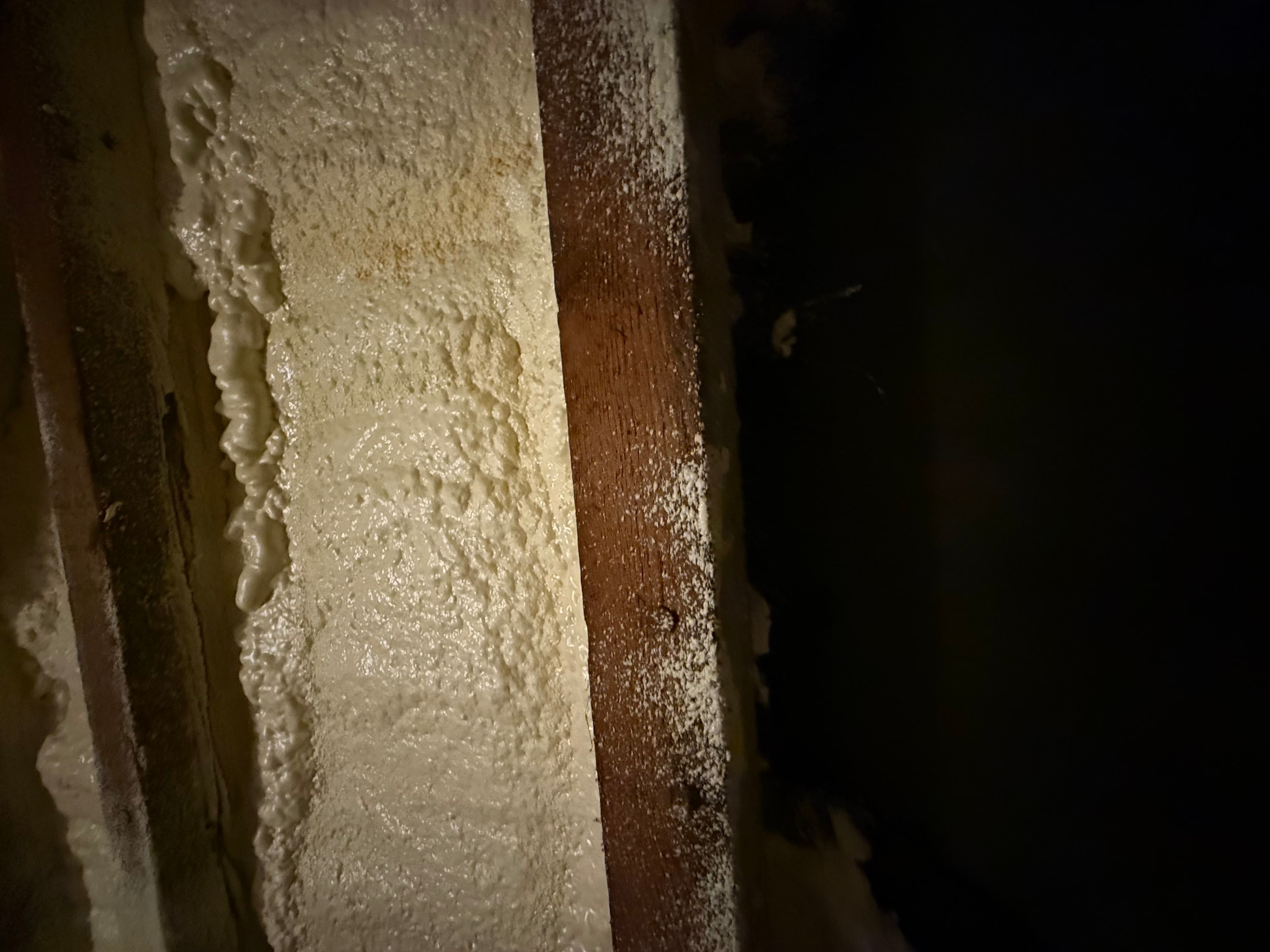 Side-by-side rafter comparison: foam-covered on the left, clean bare timber on the right after removal
